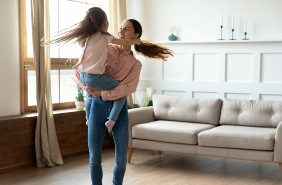 Mom holding child dancing in living room of home