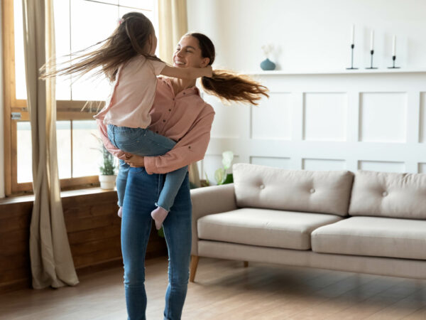 Mom holding child dancing in living room of home