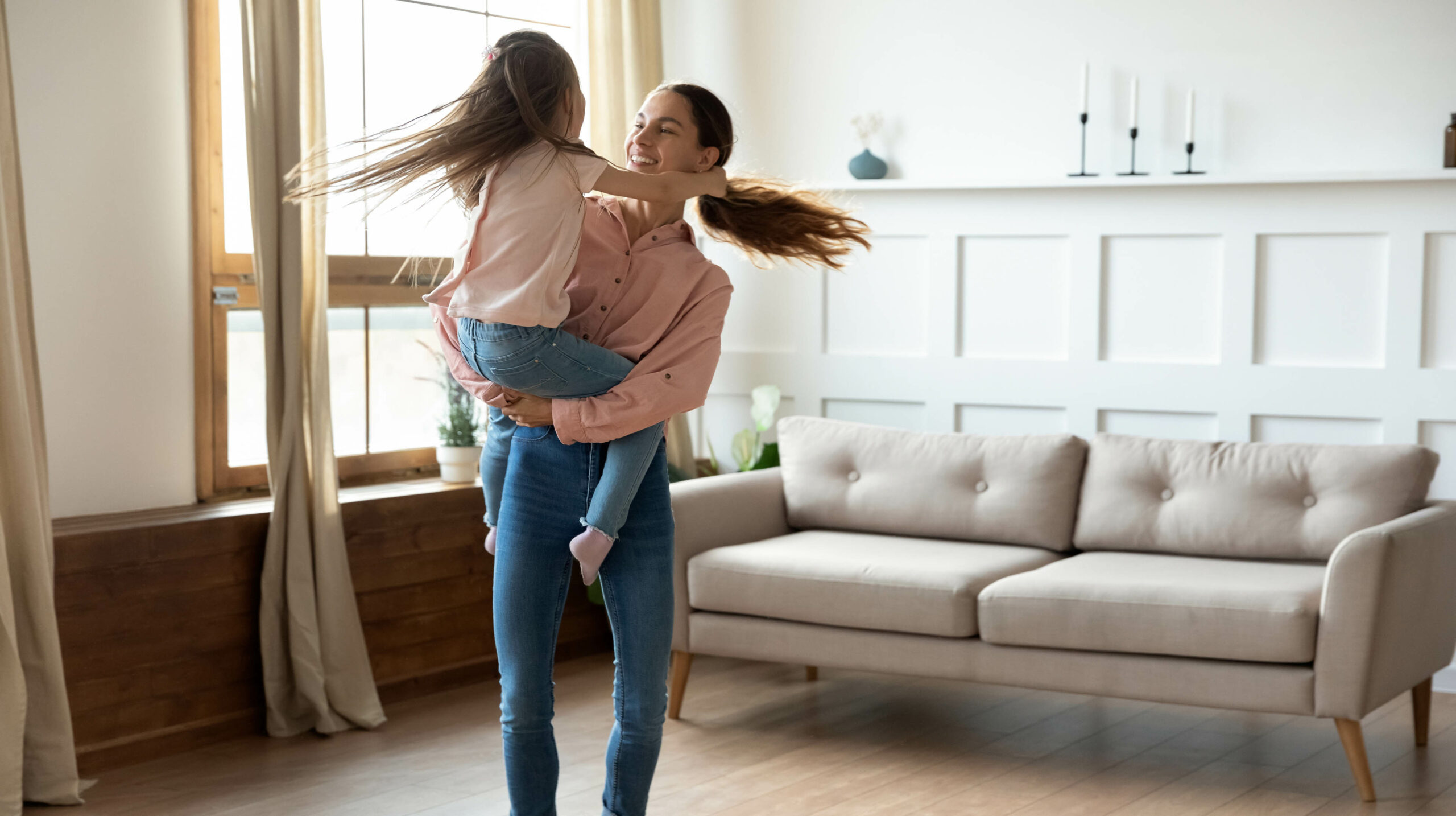 Mom holding child dancing in living room of home