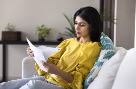Woman sitting on couch reviewing her mortgage statement.